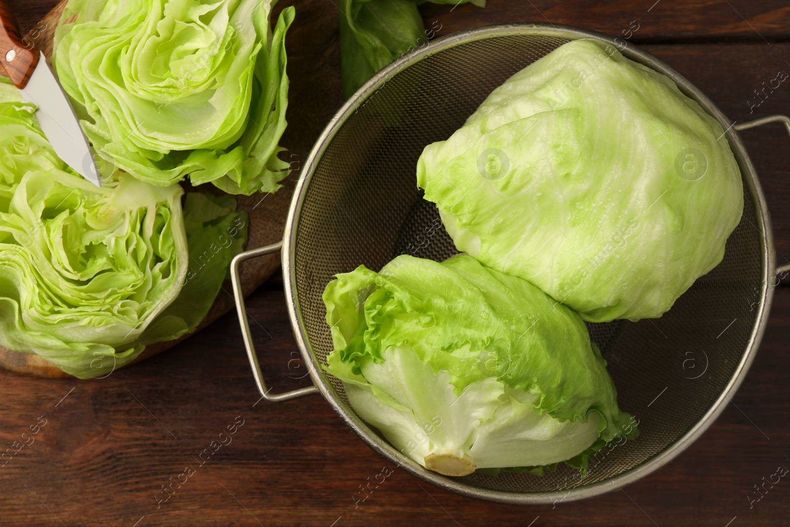 Photo of Fresh green whole and cut iceberg lettuce heads on wooden table, flat lay