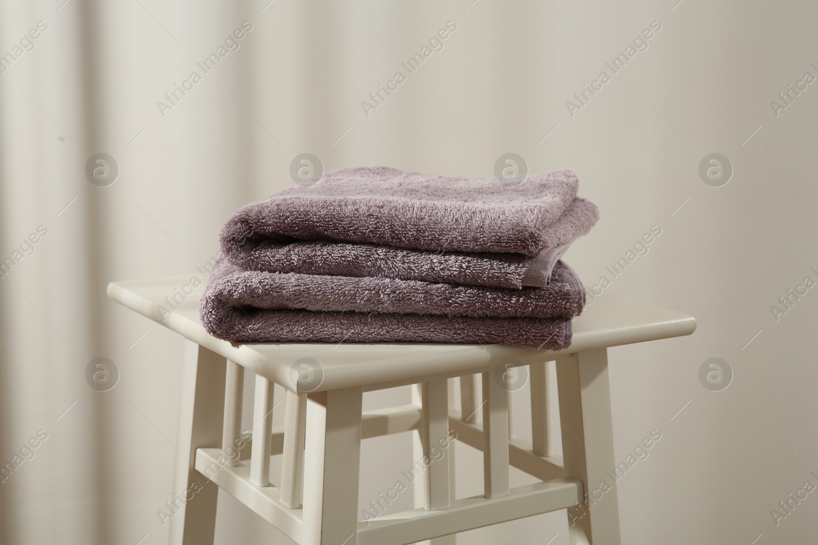 Photo of Violet towels on stool against white wall