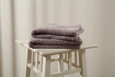 Photo of Violet towels on stool against white wall