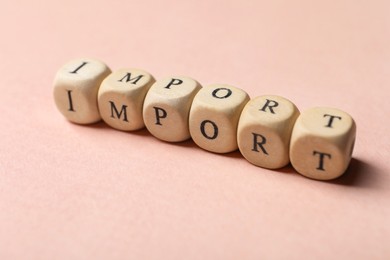 Photo of Word Import made of wooden cubes on beige background, closeup