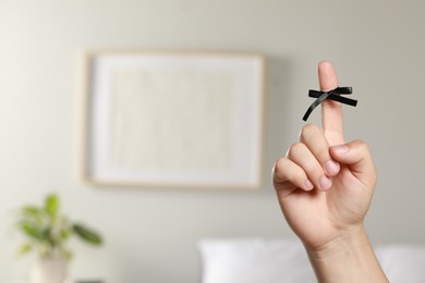 Photo of Man showing index finger with tied bow as reminder indoors, closeup. Space for text