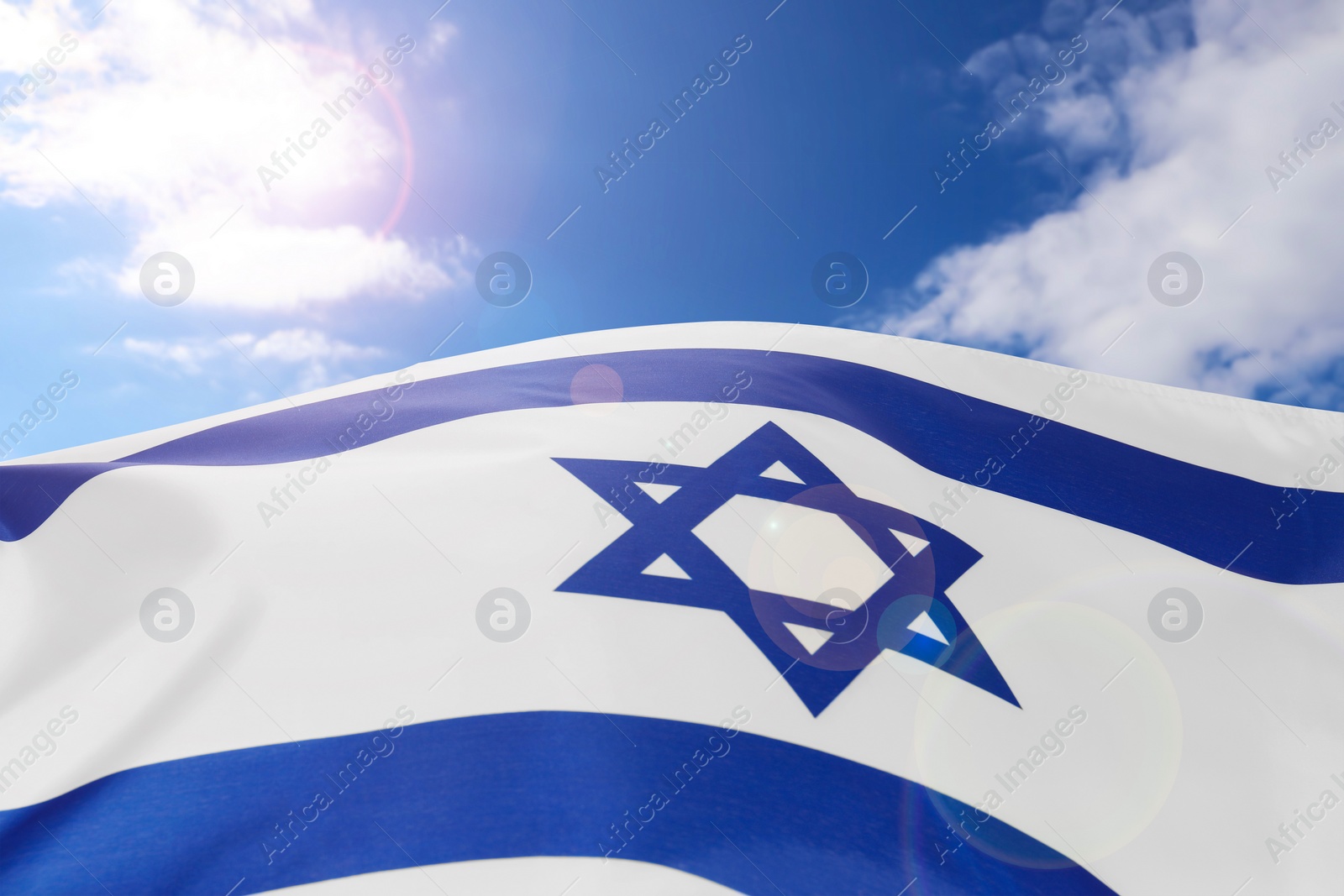 Image of National flag of Israel against blue sky with clouds