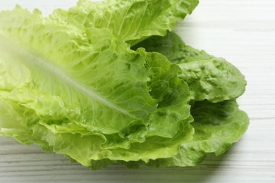 Photo of Fresh leaves of green romaine lettuce on white wooden table, closeup