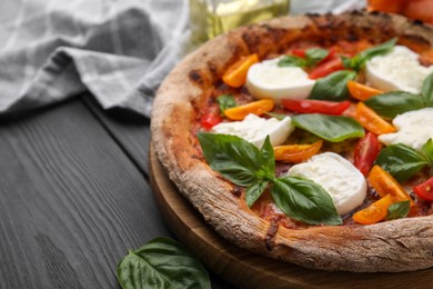 Delicious pizza with burrata cheese, tomatoes and basil on grey wooden table, closeup