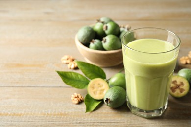 Photo of Fresh feijoa smoothie and fresh fruits on wooden table, closeup. Space for text