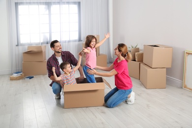 Photo of Happy family playing with cardboard box in their new house. Moving day