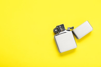 Photo of Gray metallic cigarette lighter on yellow background, top view. Space for text