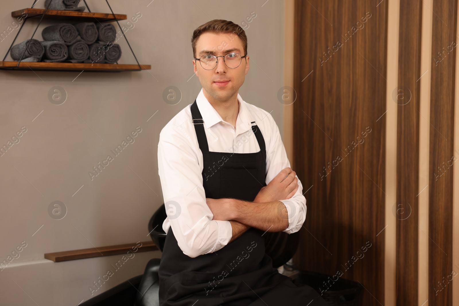 Photo of Portrait of professional hairdresser wearing apron in beauty salon