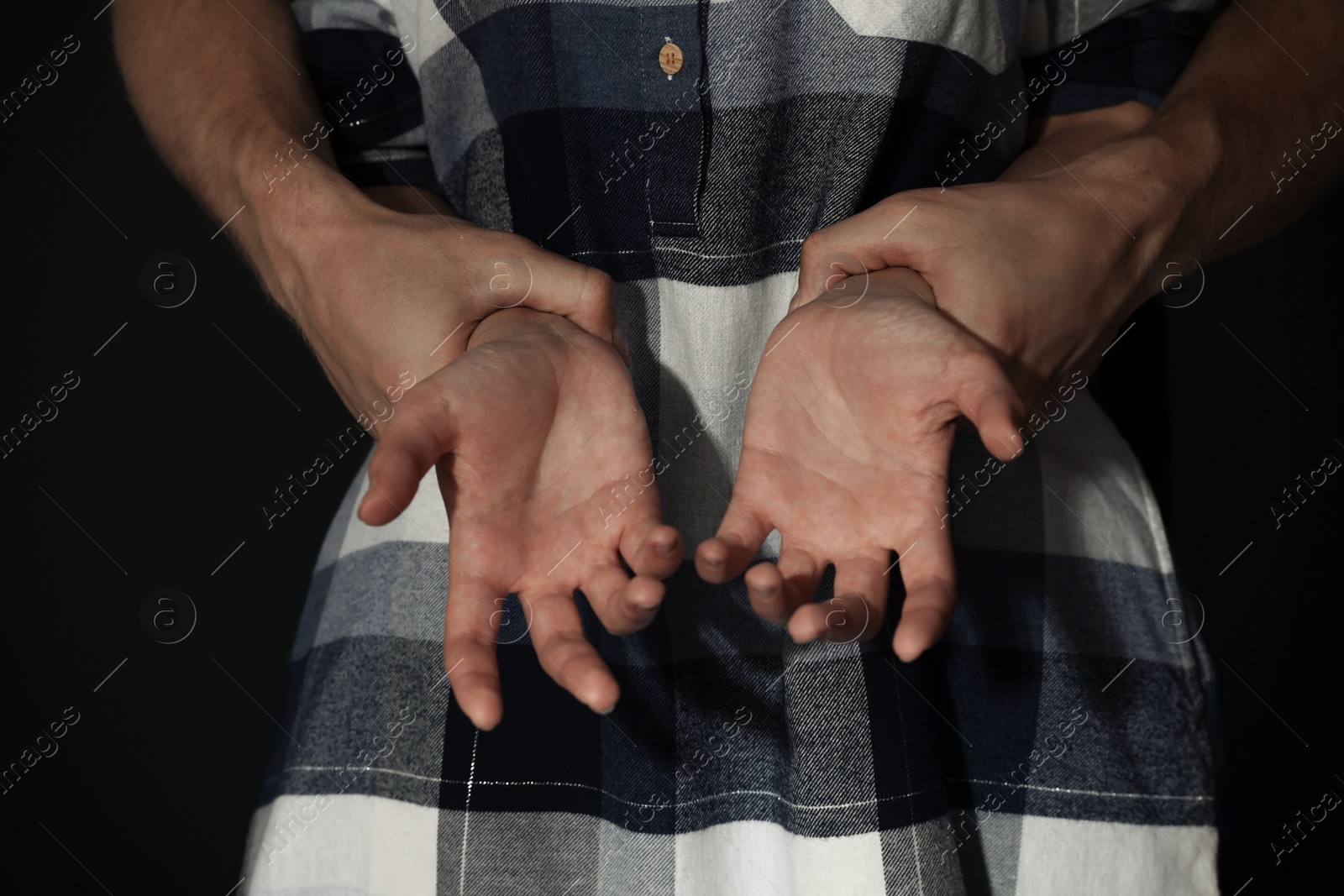 Photo of Man holding woman's hands on dark background, closeup. Stop sexual assault