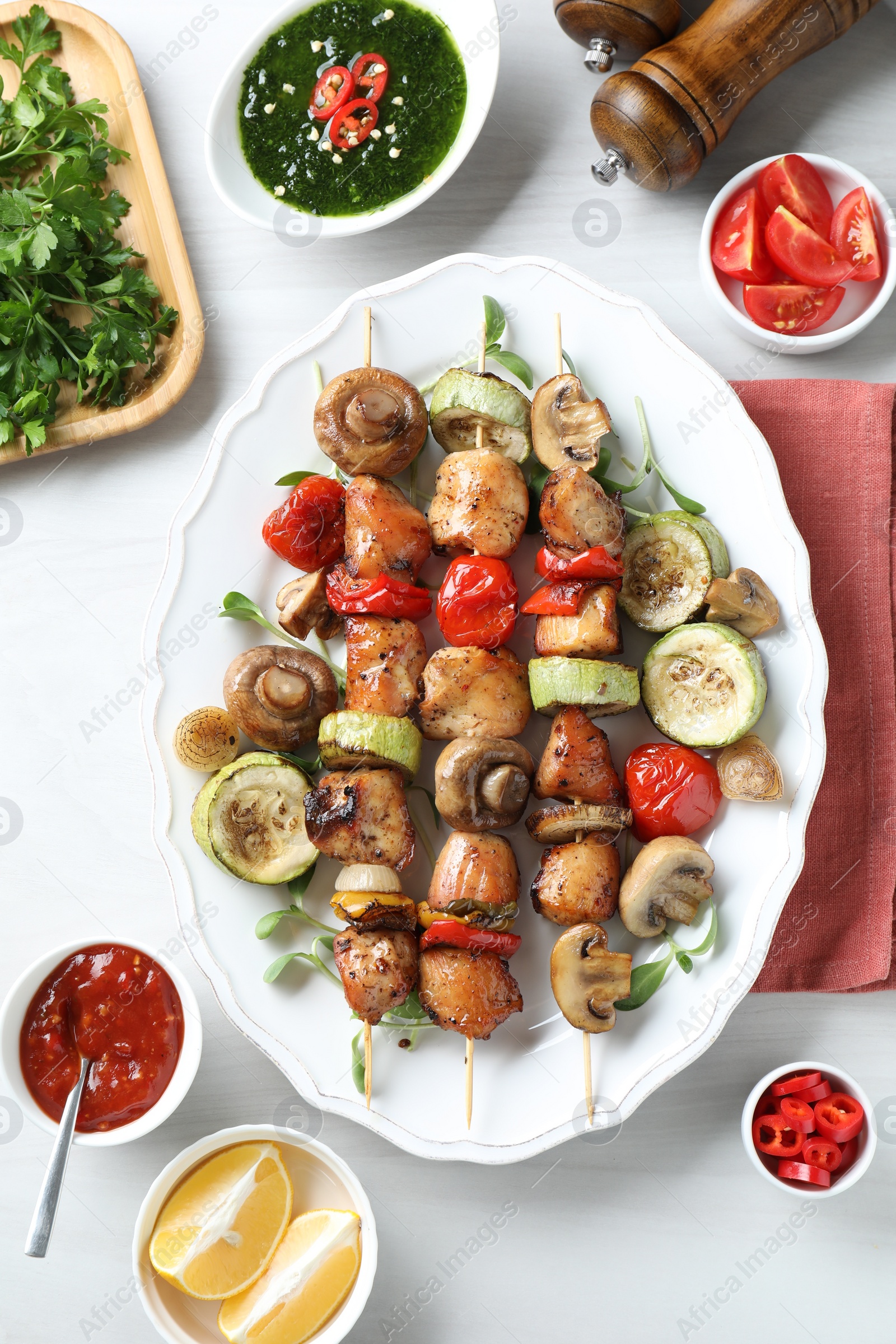 Photo of Delicious shish kebabs with vegetables and microgreens served on white table, flat lay