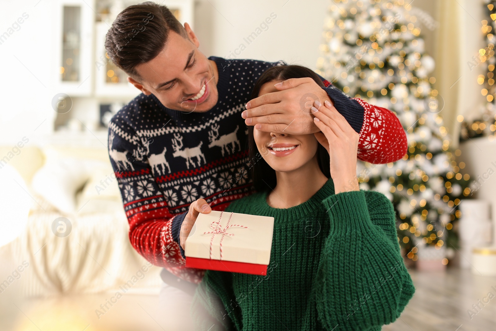 Photo of Man presenting Christmas gift to his girlfriend at home