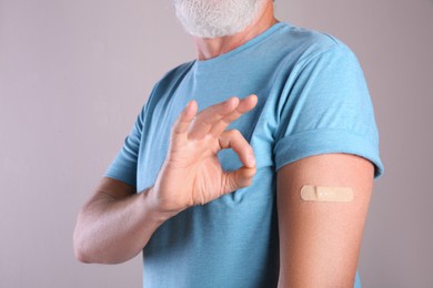 Photo of Senior man showing arm with bandage after vaccination on beige background, closeup