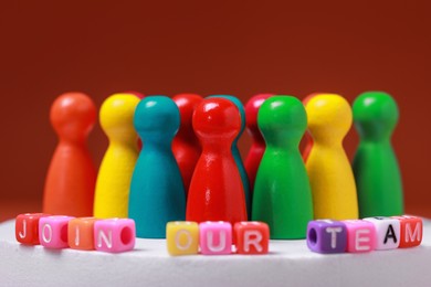 Photo of Colorful cubes with phrase Join Our Team and pawns on white round podium, closeup. Recruiter searching employee