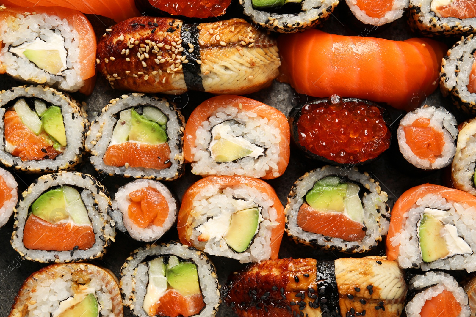 Photo of Different tasty sushi rolls as background, top view