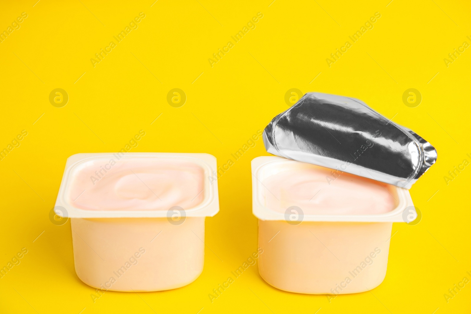 Photo of Tasty organic yogurt in plastic cups on yellow background