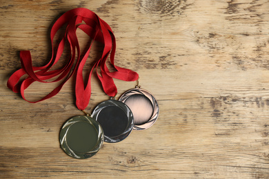 Gold, silver and bronze medals on wooden background, flat lay. Space for design