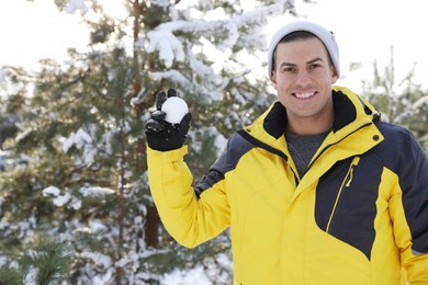Photo of Happy man with snowball outdoors on winter day. Christmas vacation