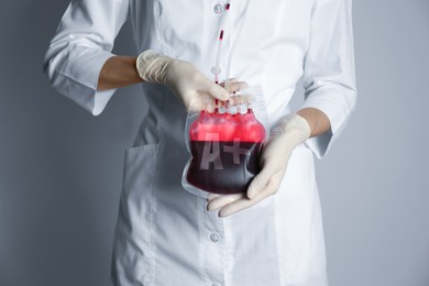 Doctor holding A+ type blood for transfusion on light grey background, closeup.
