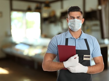 Image of Waiter in medical face mask in restaurant. Space for text