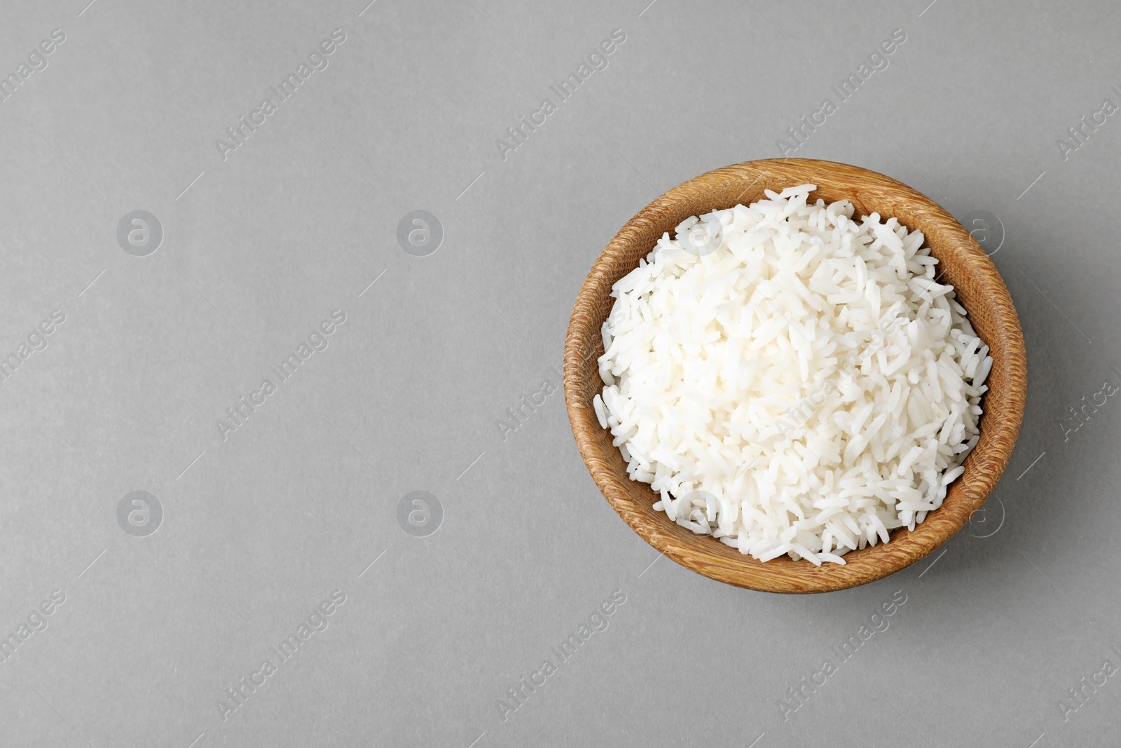 Photo of Bowl of tasty cooked rice on grey background, top view. Space for text