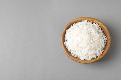 Bowl of tasty cooked rice on grey background, top view. Space for text