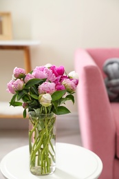 Photo of Vase with bouquet of beautiful peonies on table in room