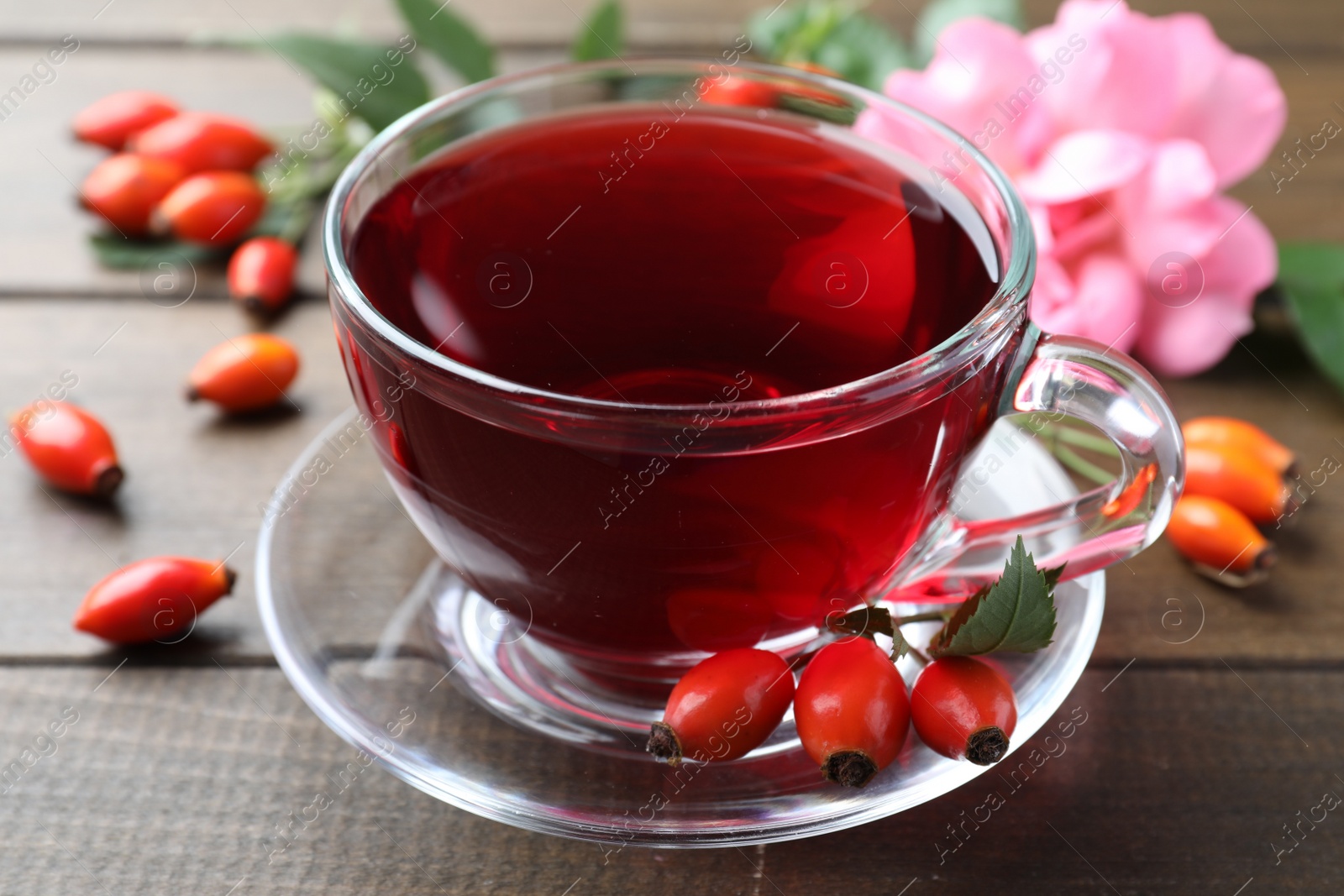 Photo of Aromatic rose hip tea and fresh berries on wooden table, closeup