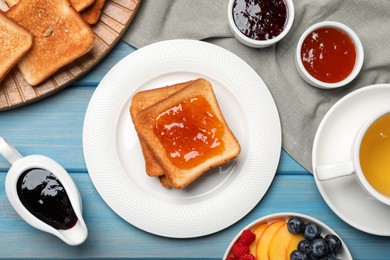 Photo of Tasty toasts served with different jam on light blue wooden table, flat lay