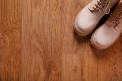 Pair of stylish beige leather shoes on wooden floor, top view. Space for text