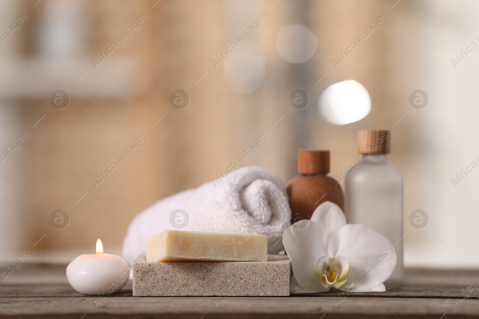 Photo of Composition with spa products and beautiful orchid flower on wooden table against blurred background