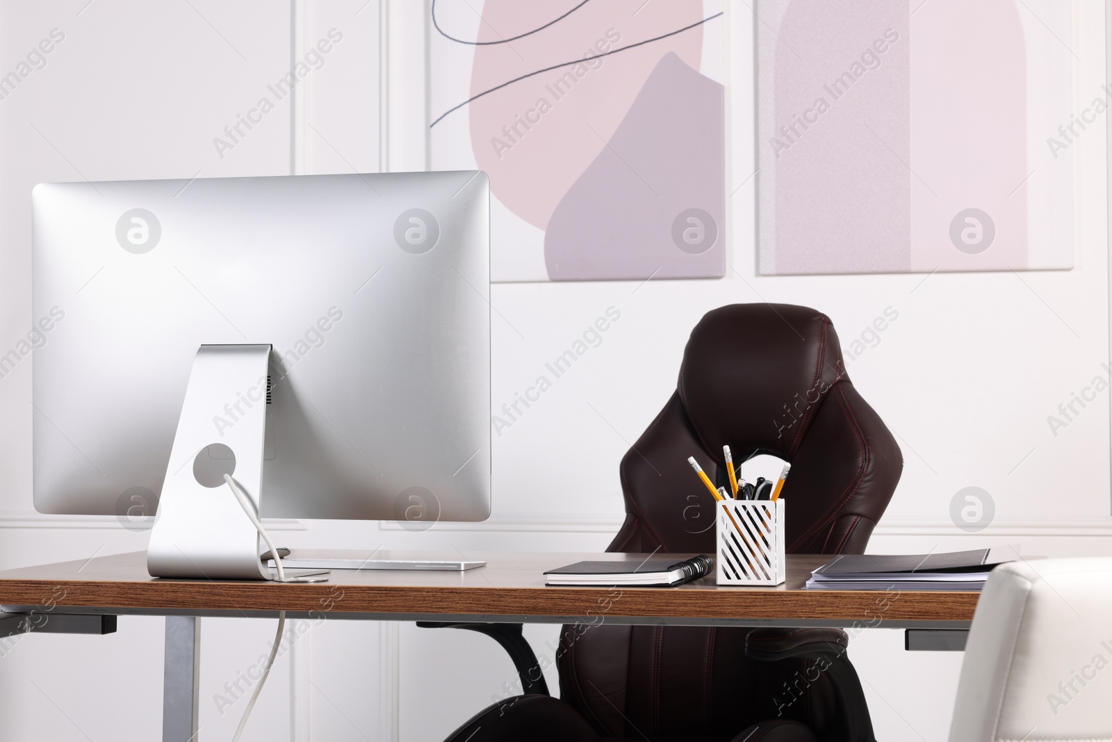 Photo of Director's workplace with wooden table, computer and comfortable armchairs. Interior design