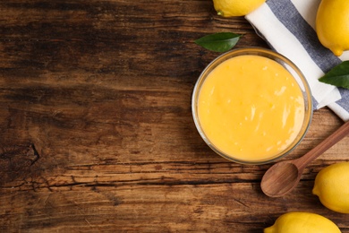 Photo of Delicious lemon curd and fresh fruits on wooden table, flat lay. Space for text