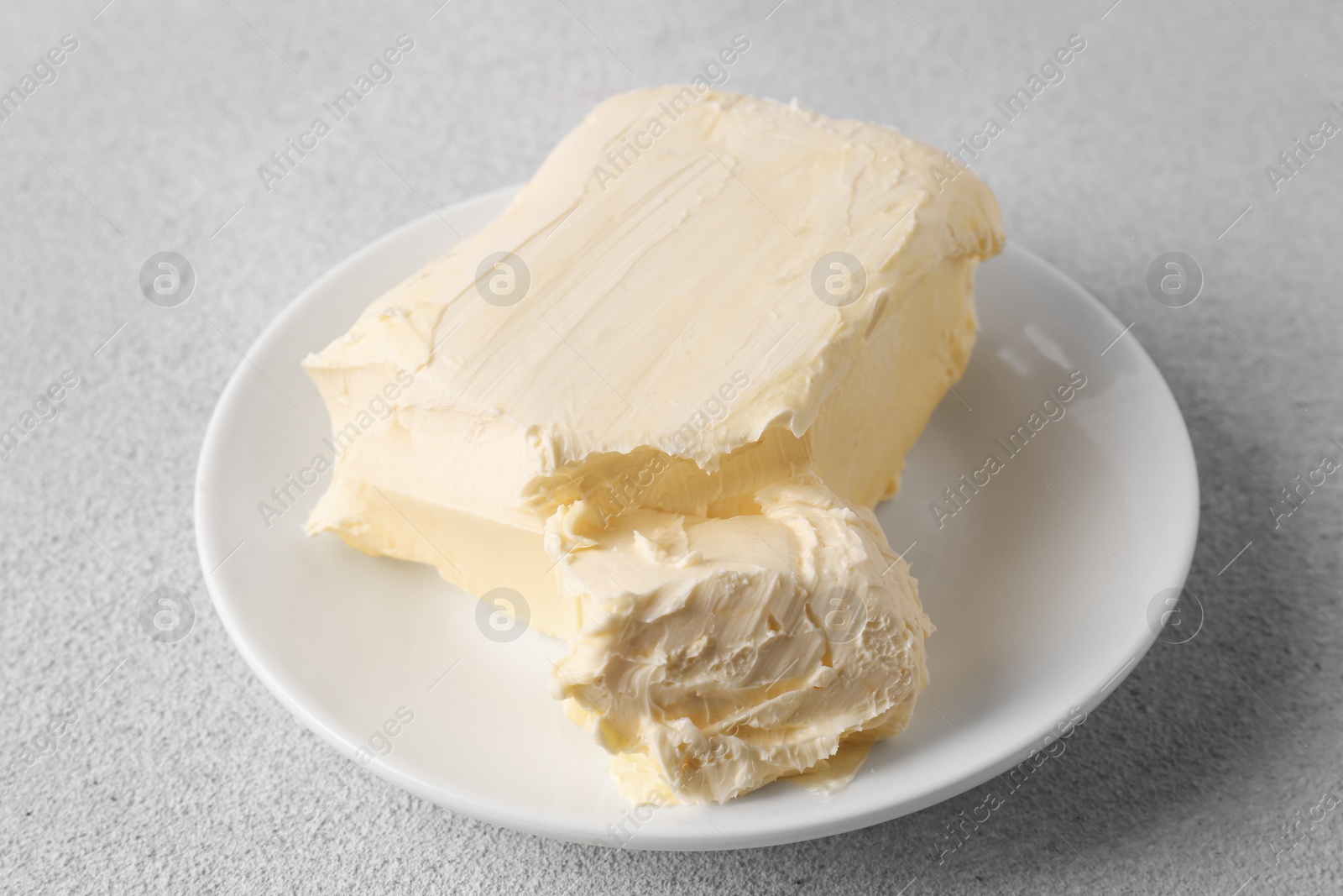 Photo of Plate with tasty homemade butter on white textured table
