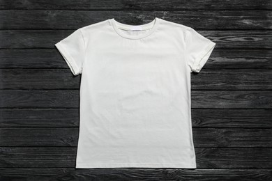 Photo of Stylish white t-shirt on black wooden background, top view