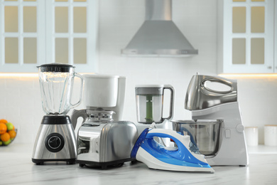 Photo of Set of modern home appliances on white marble table in kitchen