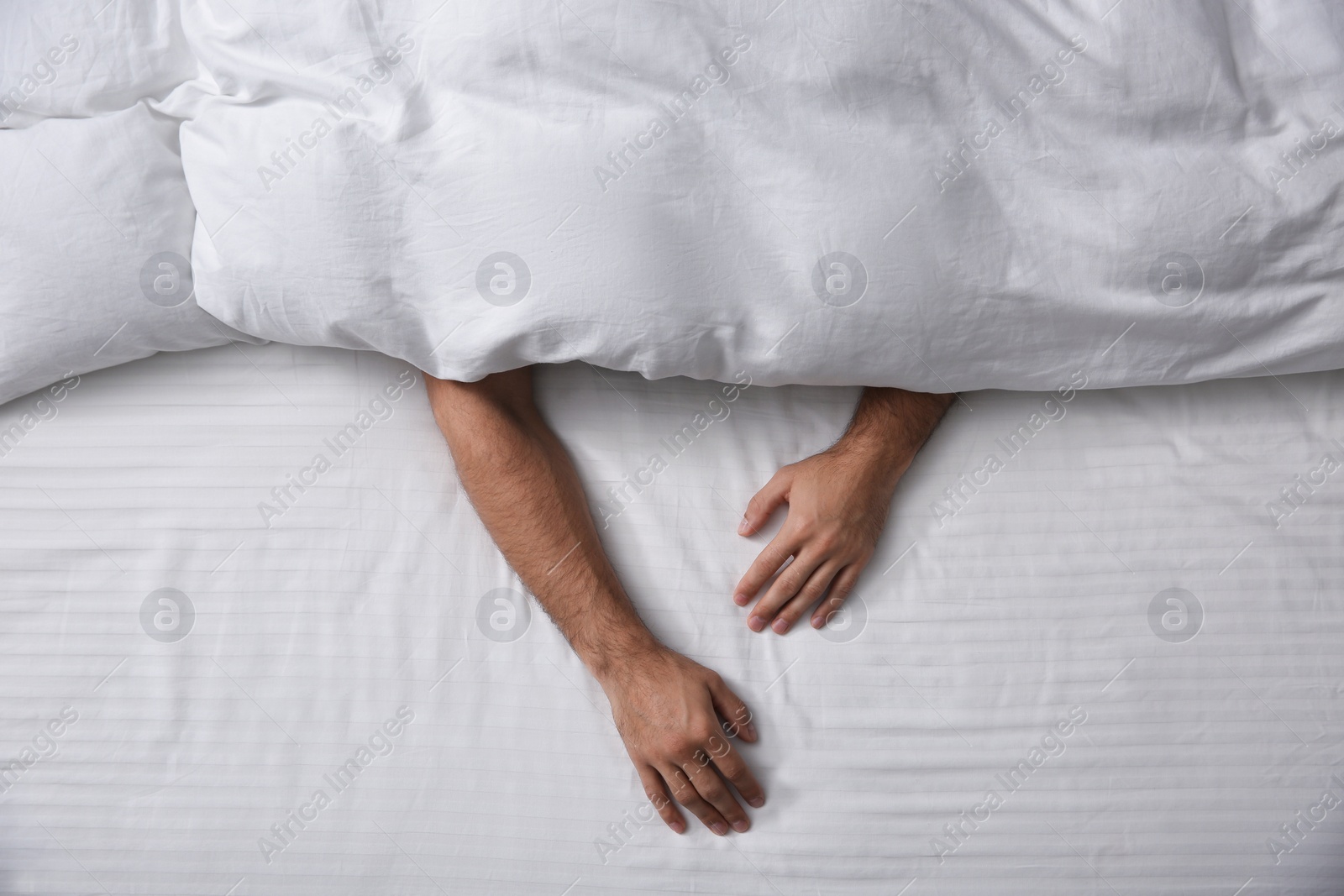 Photo of Man sleeping under soft blanket in bed at home, top view