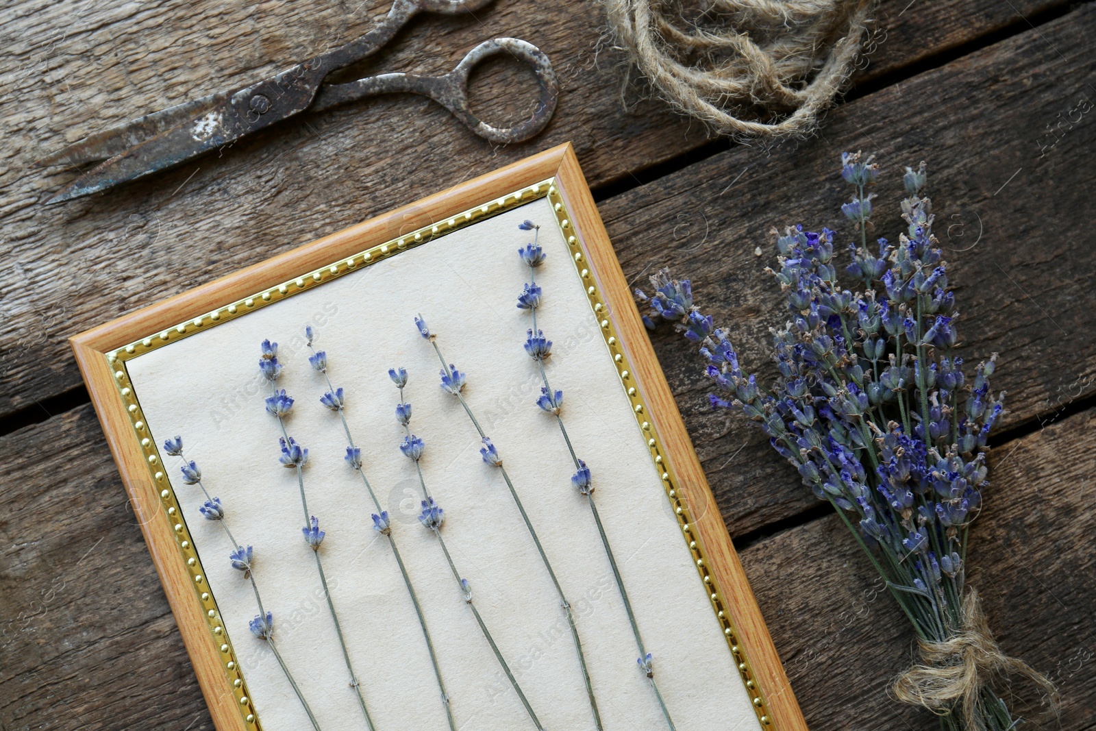 Photo of Beautiful lavender flowers, frame, twine and scissors on wooden table, flat lay