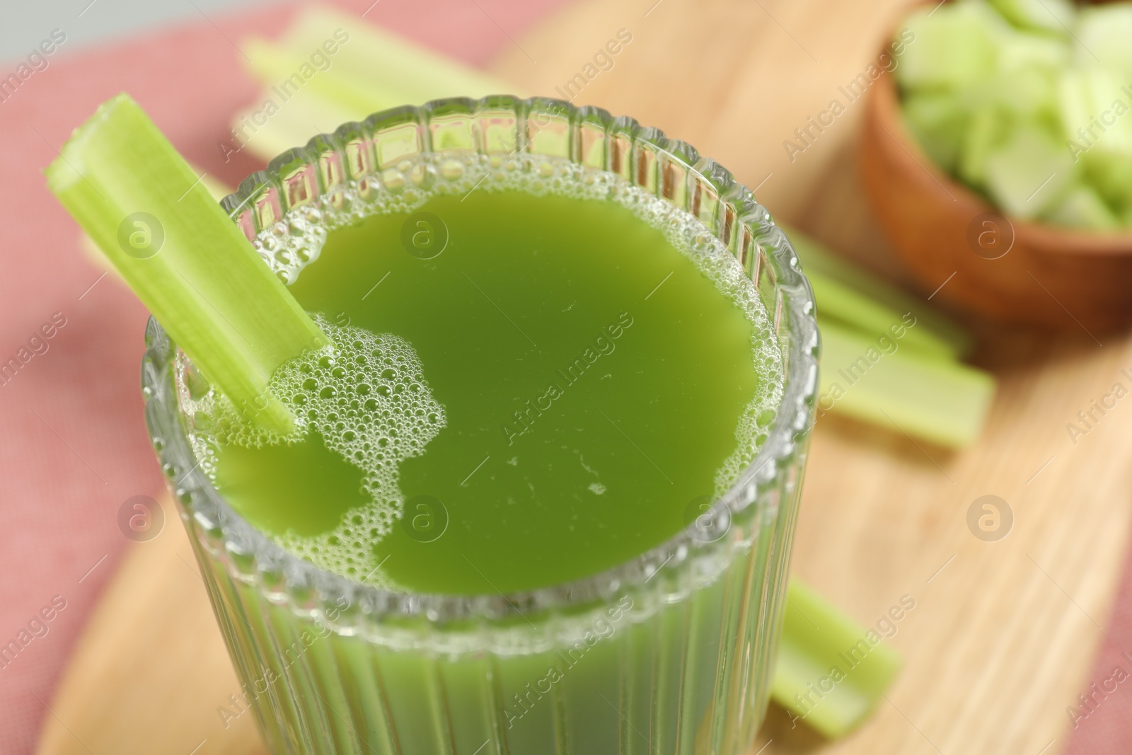 Photo of Glass of delicious celery juice and vegetables on wooden board, closeup