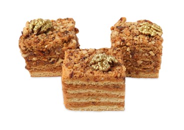 Photo of Pieces of layered honey cake with walnuts on white background