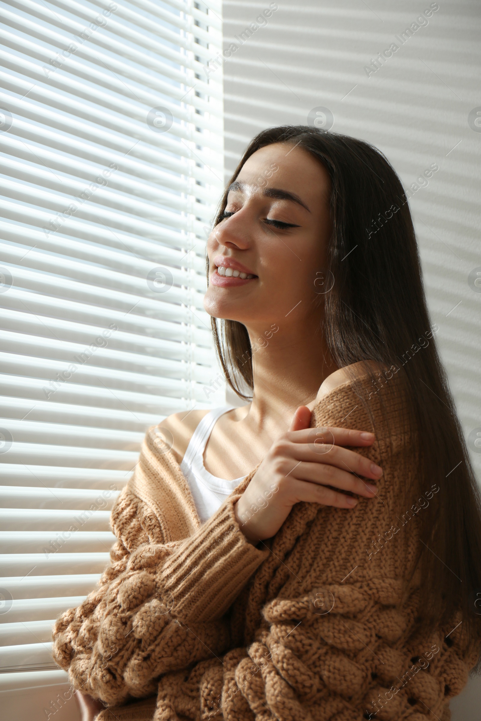 Photo of Young woman near window with Venetian blinds