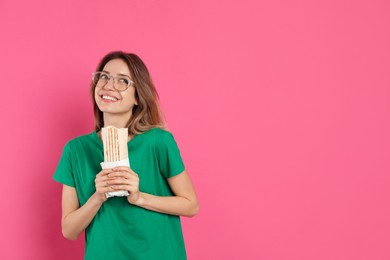 Photo of Young woman with delicious shawarma on pink background, space for text