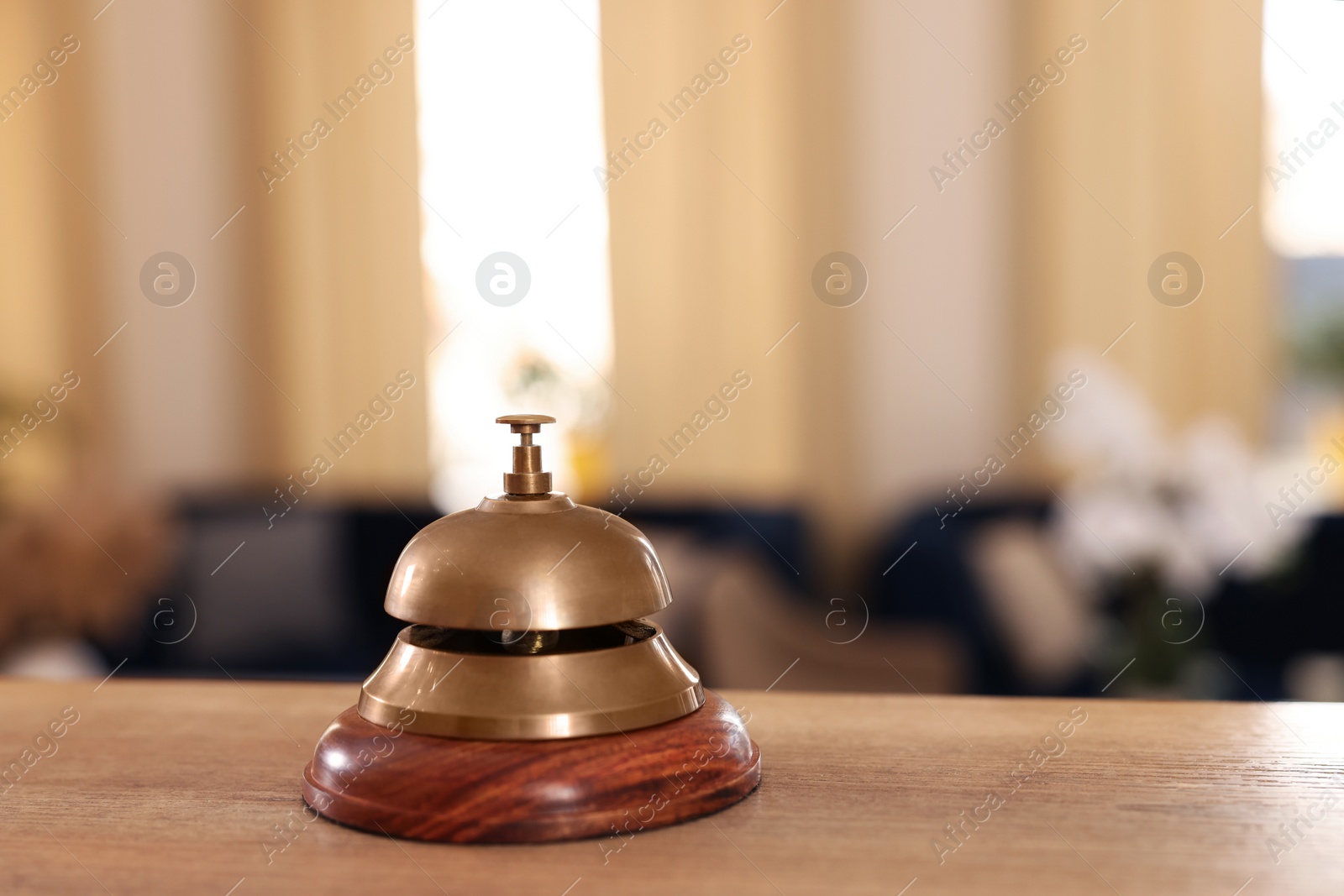 Photo of Hotel service bell on wooden reception desk. Space for text