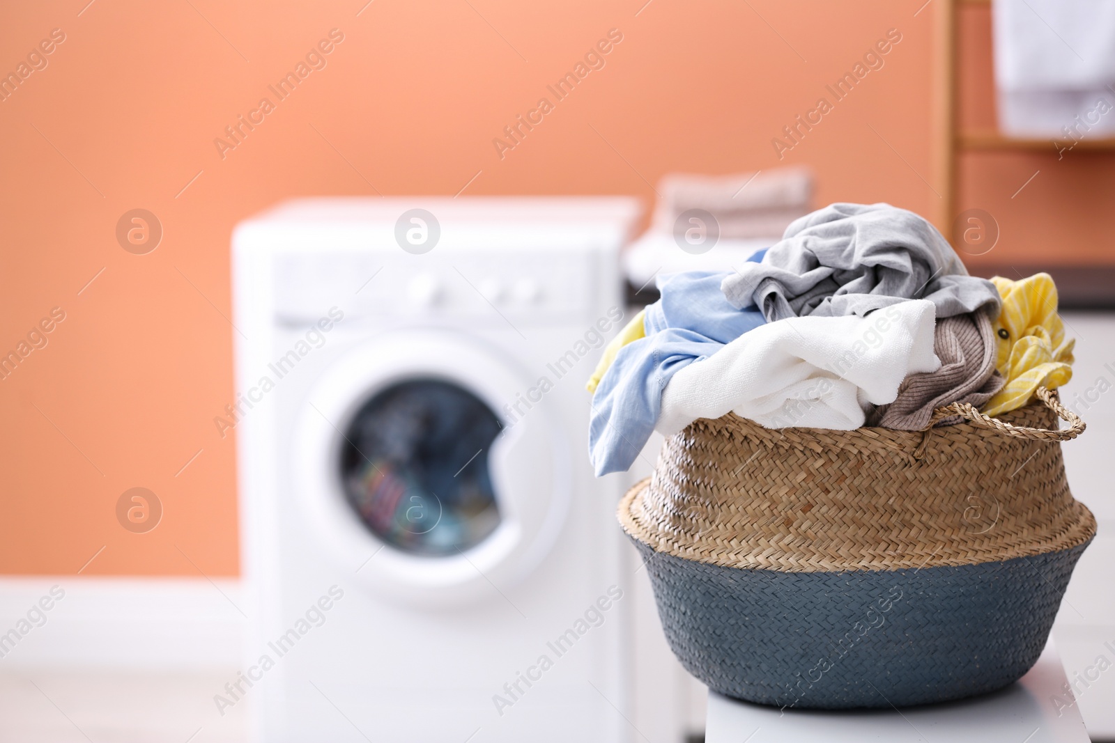 Photo of Wicker basket with dirty laundry indoors, space for text