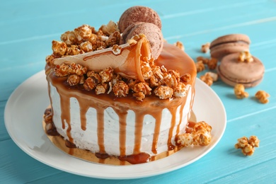 Photo of Delicious homemade cake with caramel sauce and popcorn on table