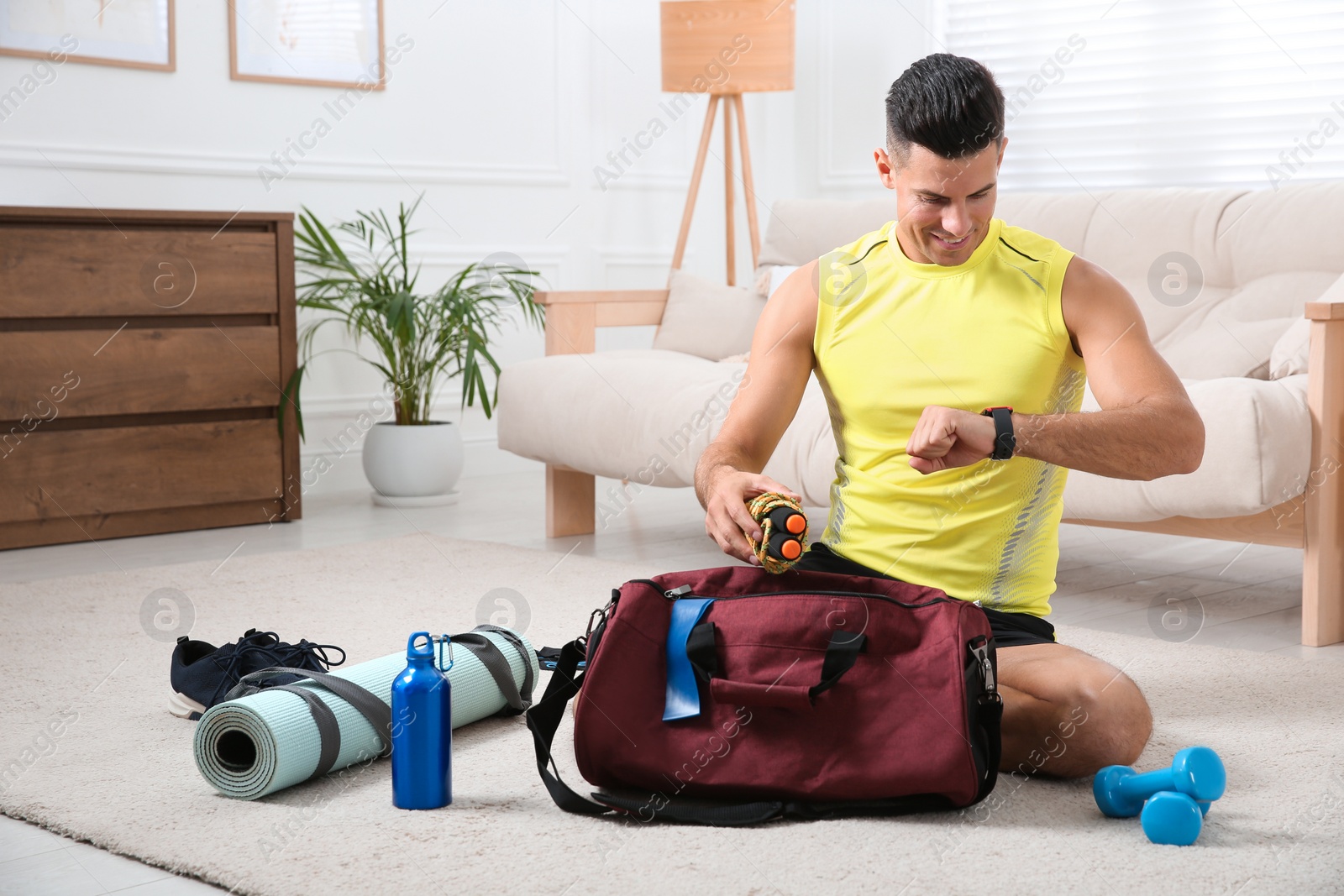 Photo of Man packing sports stuff for training into bag at home