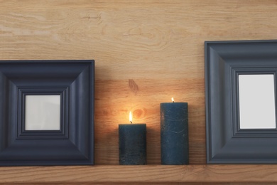 Photo of Shelf with burning candles against wooden wall