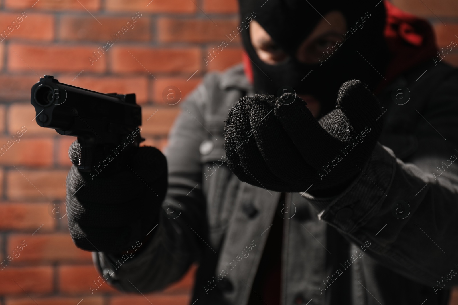 Photo of Dangerous criminal with gun near brick wall, selective focus. Armed robbery