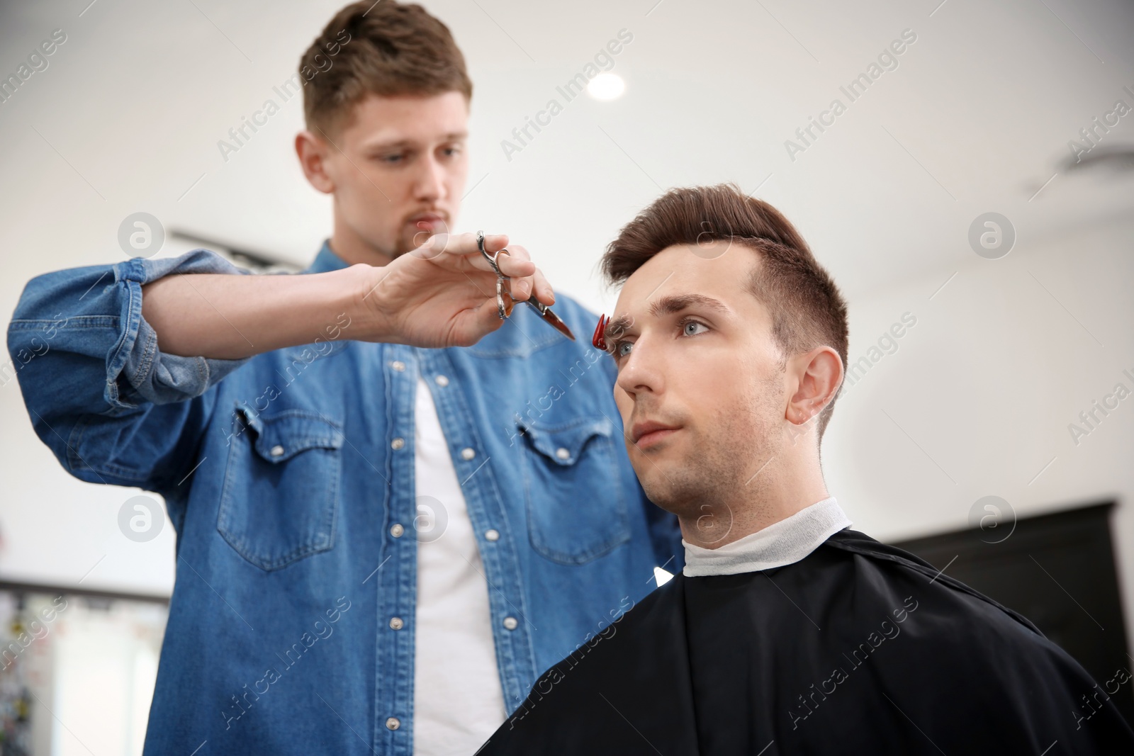 Photo of Professional barber working with client in hairdressing salon. Hipster fashion