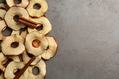 Photo of Delicious apple chips and cinnamon on grey table, flat lay. Space for text