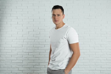 Photo of Handsome young man near white brick wall